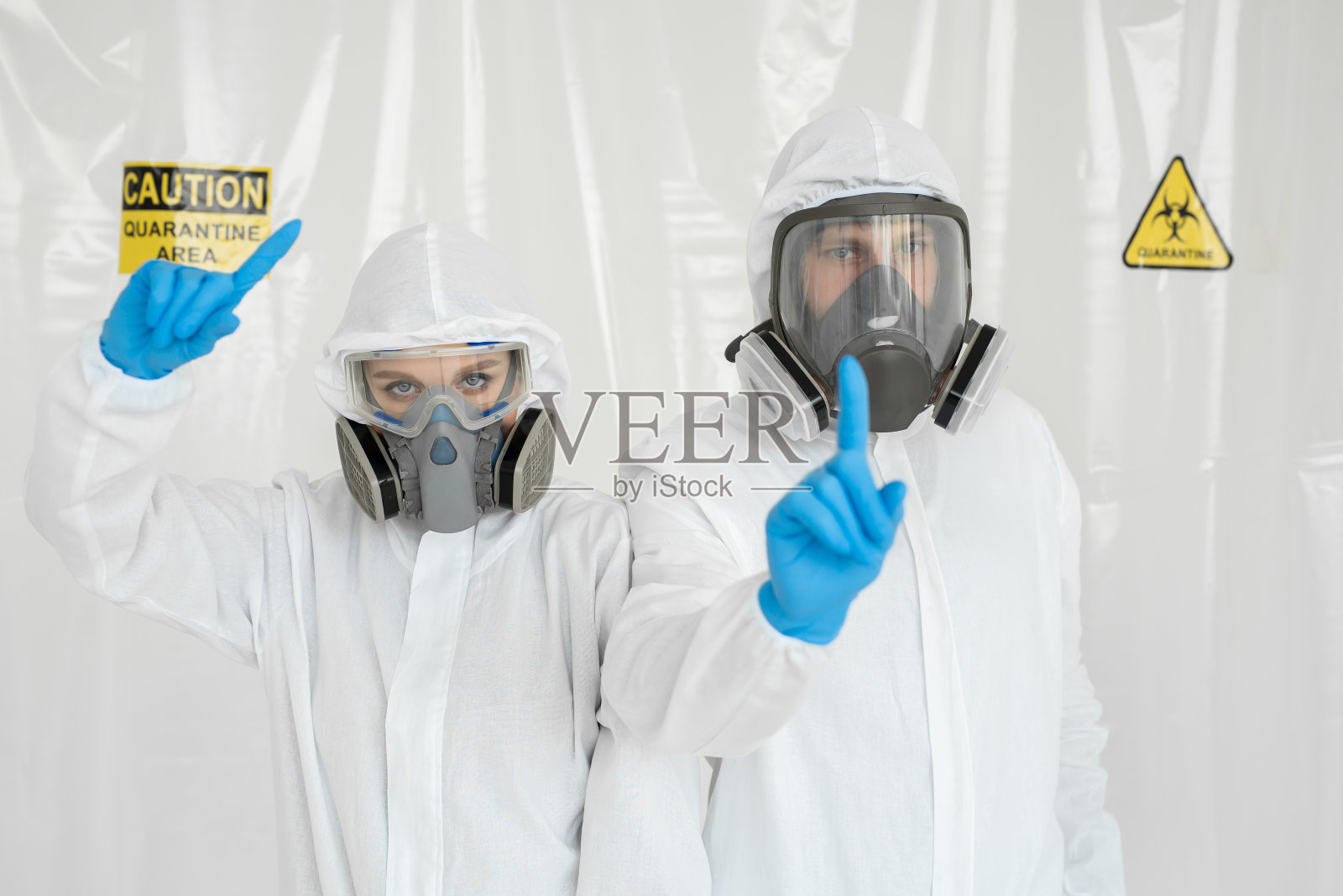 两名医生穿着防护服，戴着呼吸器，他们用手表示关注。照片摄影图片