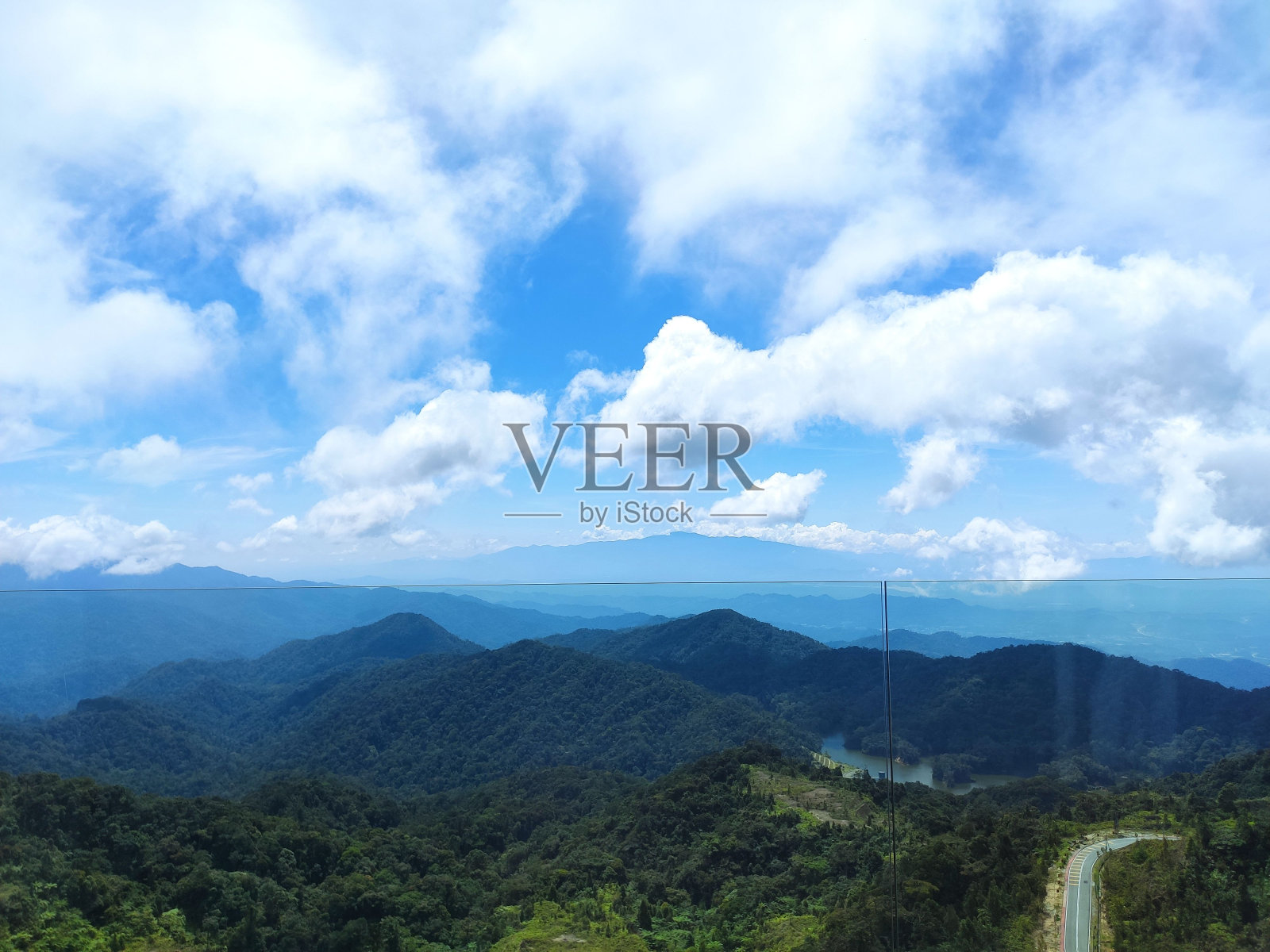 在多云的日子里，一条公路在绿色的山上鸟瞰照片摄影图片