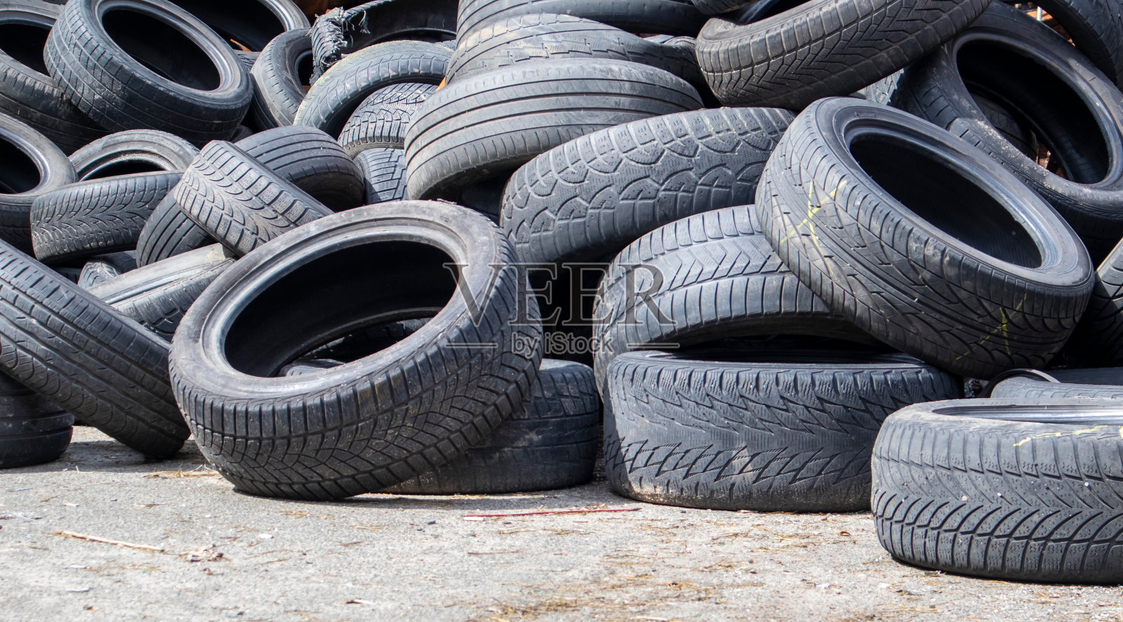 从一堆黑色旧汽车轮胎里捡来的垃圾。环境污染。生态问题。旧汽车轮胎被扔进工业垃圾填埋场进行回收。废旧橡胶轮胎的再利用。照片摄影图片