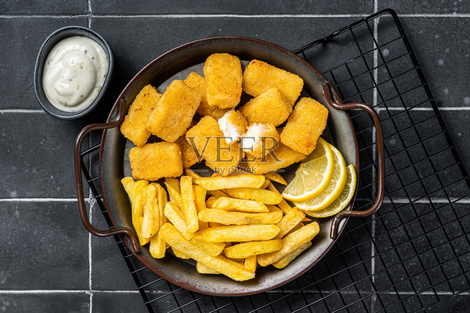 炸鱼薯条，炸鱼条和薯条放在钢托盘里，蘸酱。黑色背景。俯视图照片摄影图片