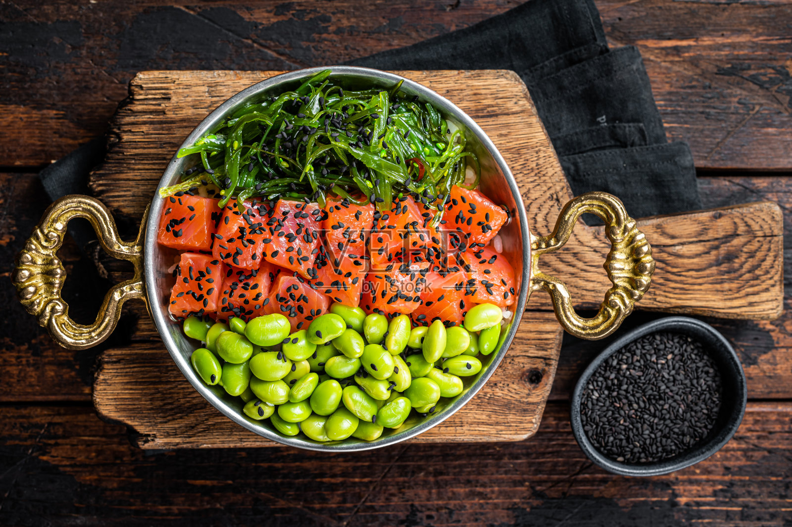 三文鱼泡碗，配鲜鱼，米饭，海带，毛豆，黑芝麻。木制背景。俯视图照片摄影图片