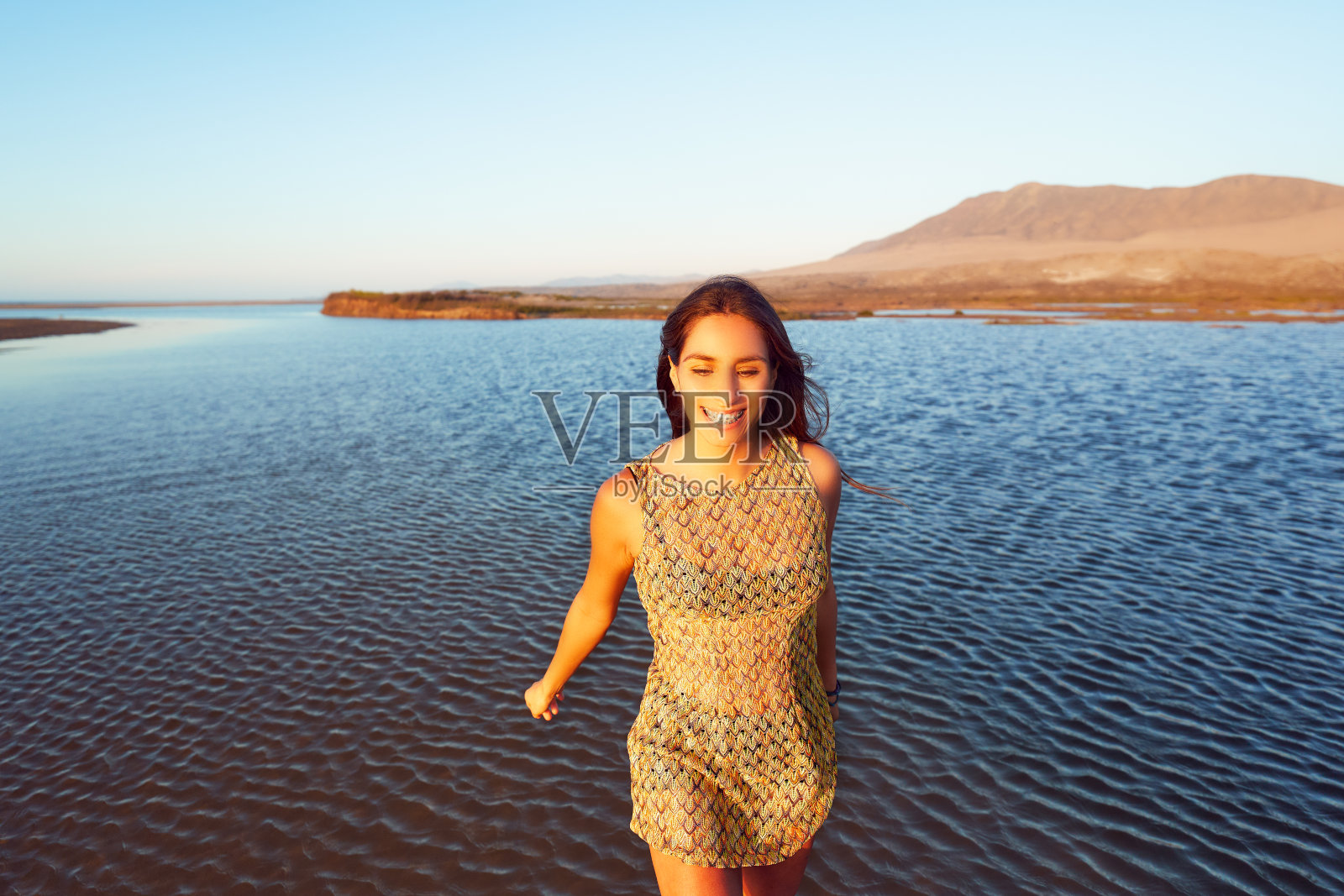 年轻的拉丁美洲妇女在沙漠景观的湿地水中快乐地行走照片摄影图片