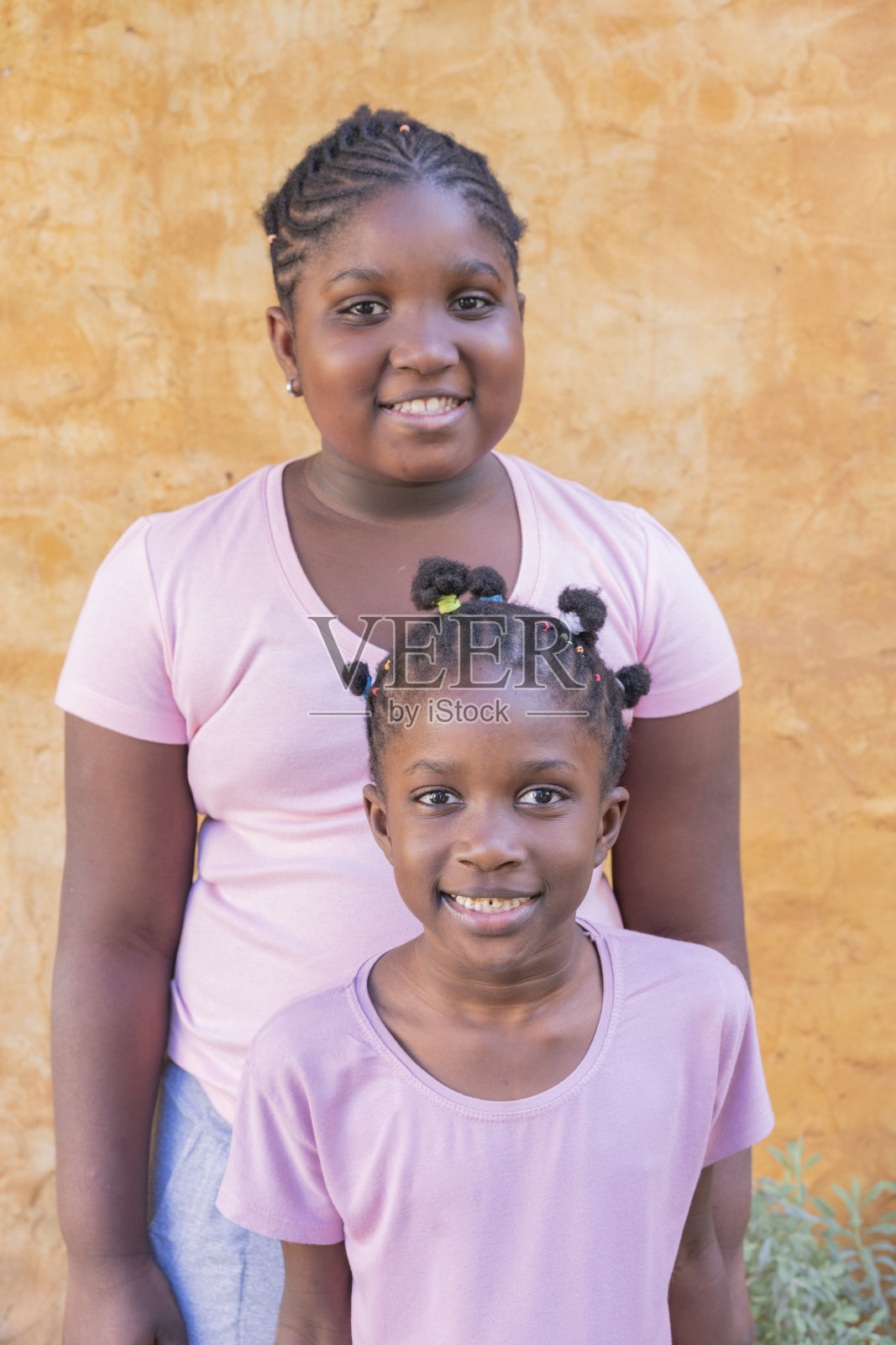 幸福的美国黑人小姐妹在户外墙背景前一起微笑的肖像照片摄影图片