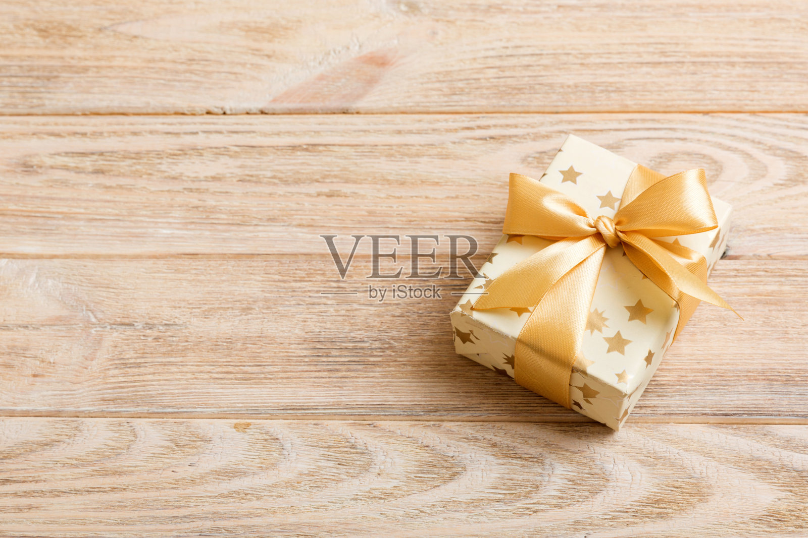 用白色包装纸包装圣诞节或其他节日手工制作的礼物，并在彩色背景上系上金色丝带。礼品盒，彩色桌子上的礼品装饰，顶部视图与复制空间照片摄影图片