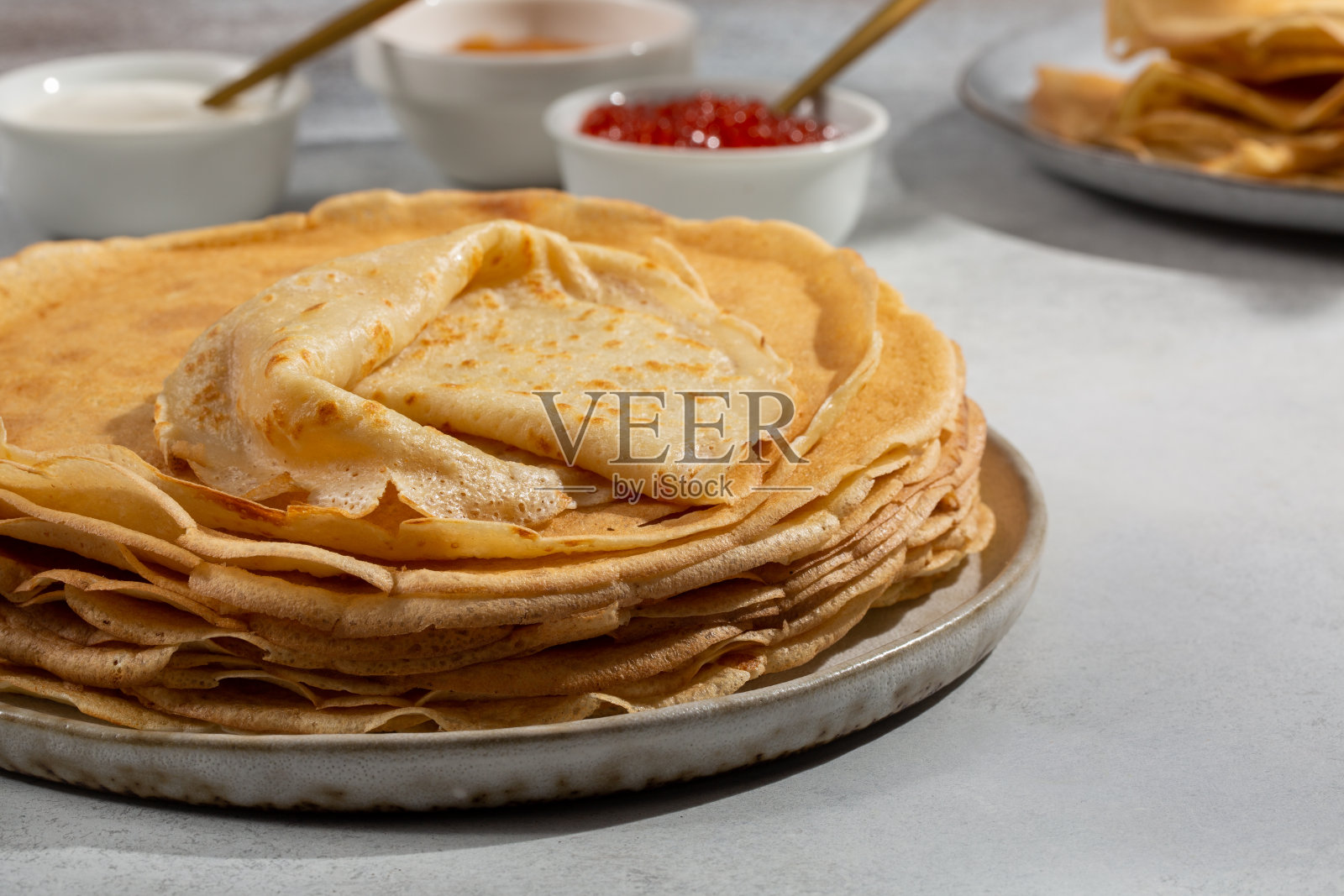 灰色桌子上的可丽饼。薄煎饼配果酱和酸奶油。照片摄影图片