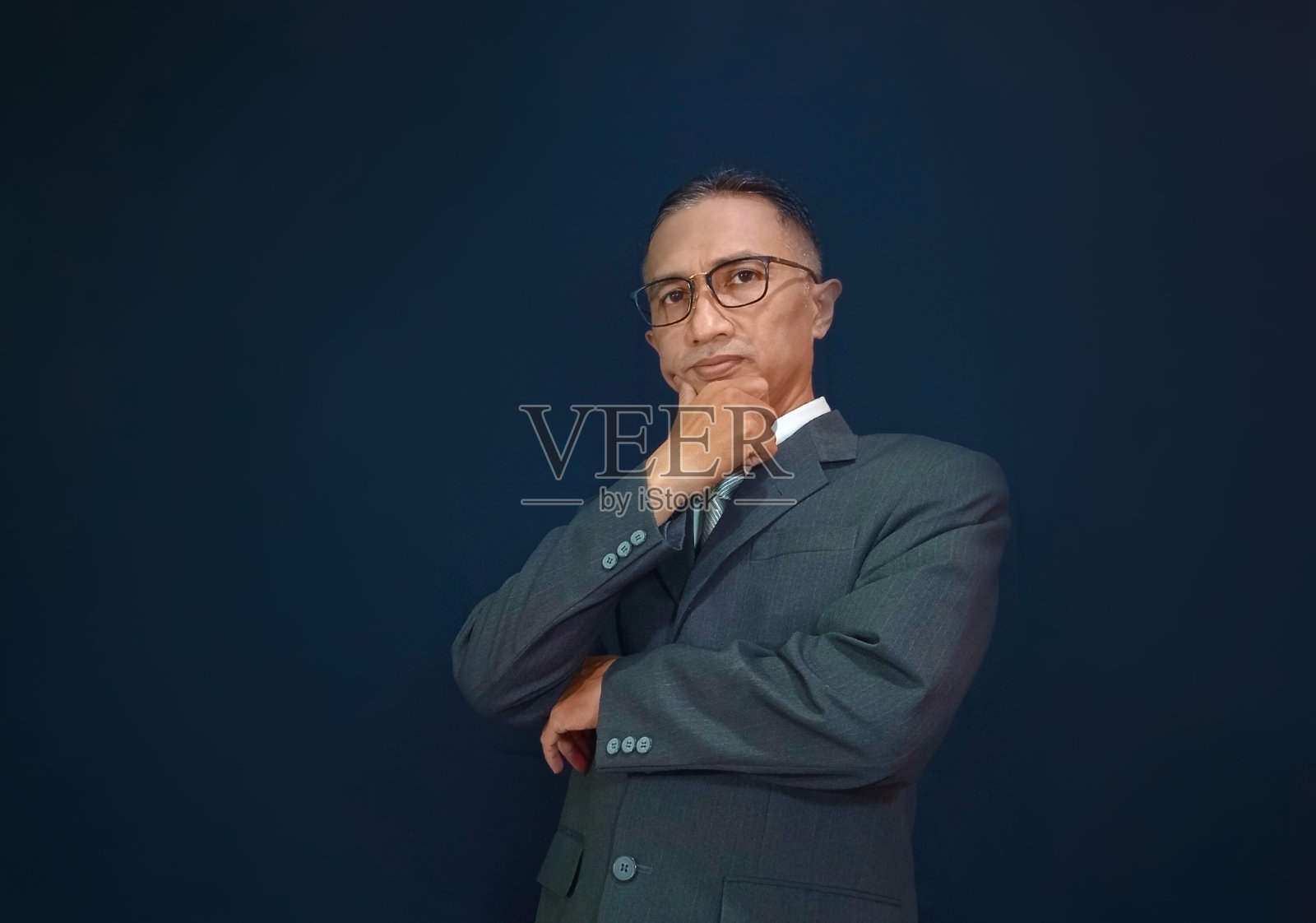 商人交叉着双臂看着镜头。照片摄影图片