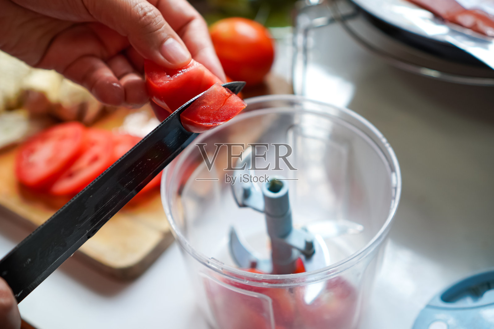 图为用搅拌器将西红柿切成小块制作番茄汤的演示。照片摄影图片