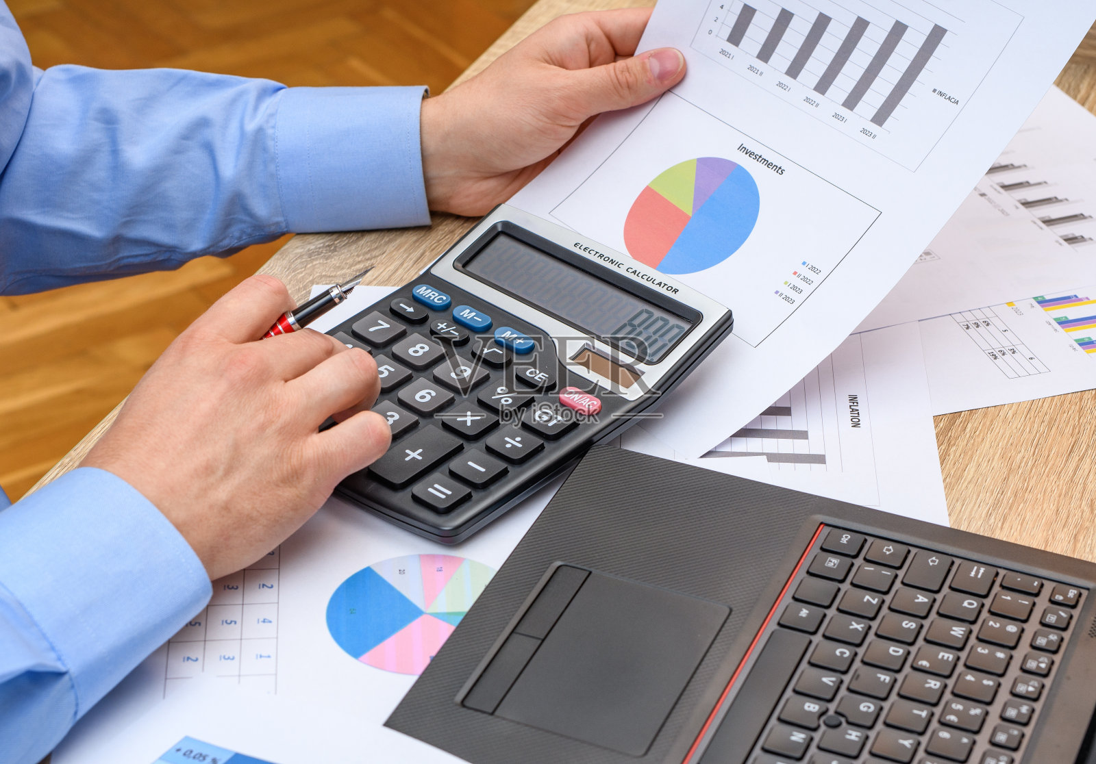 一名男子在桌前使用计算器和电脑工作照片摄影图片