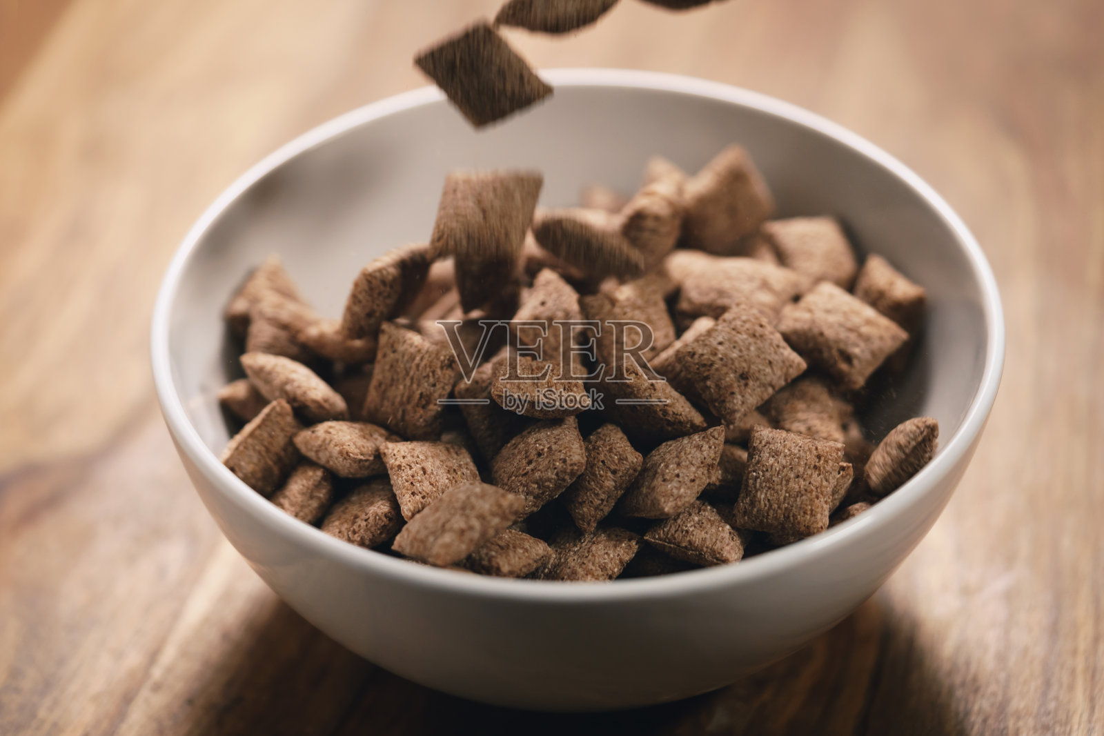 巧克力麦片枕头掉到桌子上的白色碗里照片摄影图片