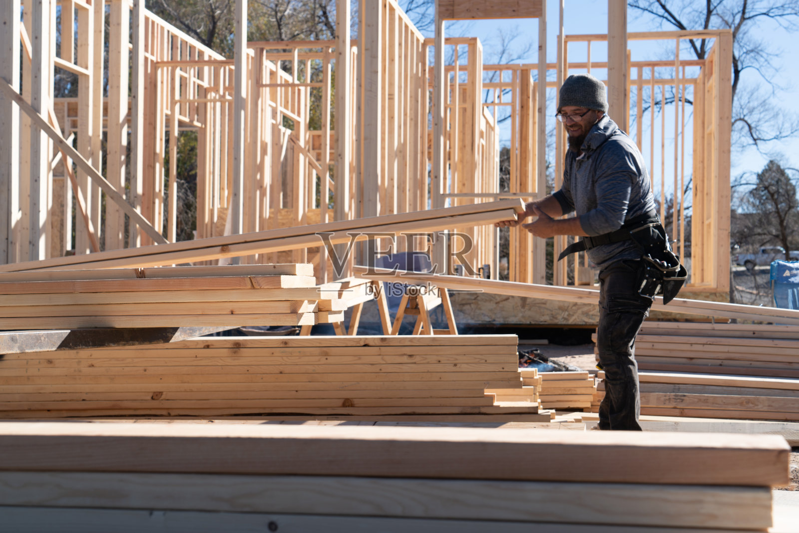 背景中的建筑工人正在搬运木材照片摄影图片