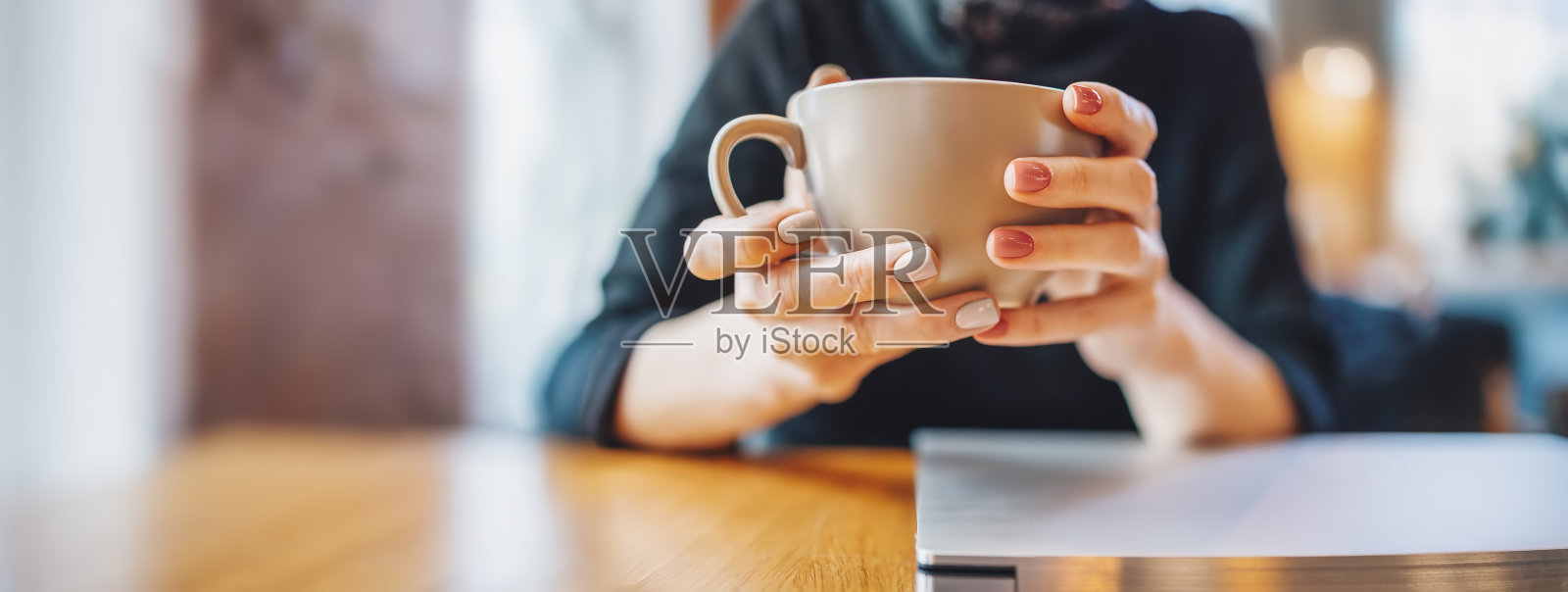 坐在咖啡桌旁的女人。她手里拿着一杯咖啡。照片摄影图片