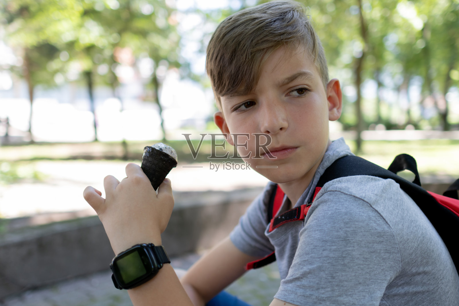 男孩在公园里吃冰淇淋。照片摄影图片