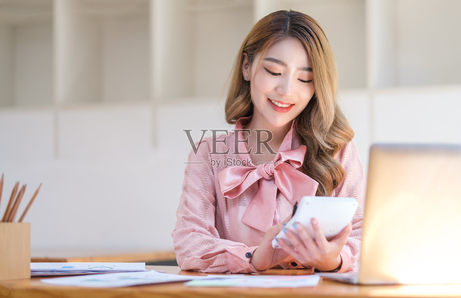 漂亮的女会计在办公室用计算器核对财务数据或销售报告。照片摄影图片