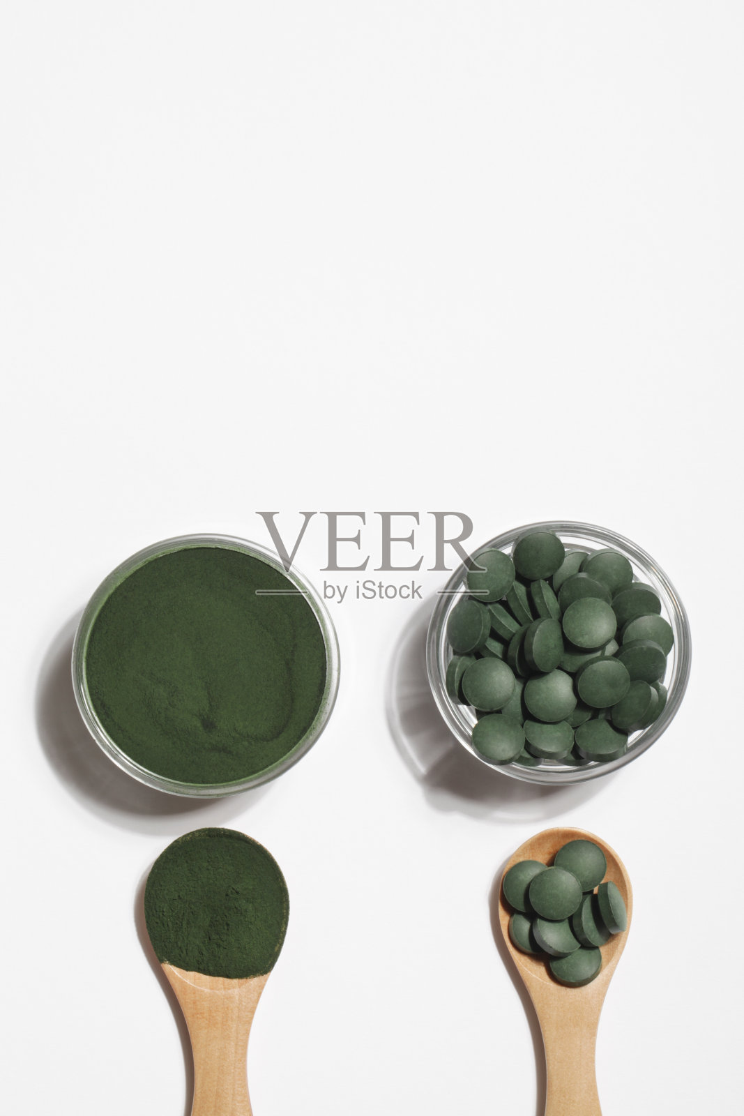 天然添加剂和超级食品。绿色的螺旋藻粉和药丸装在白色背景的玻璃碗里。健康的生活方式的概念。有机食品照片摄影图片
