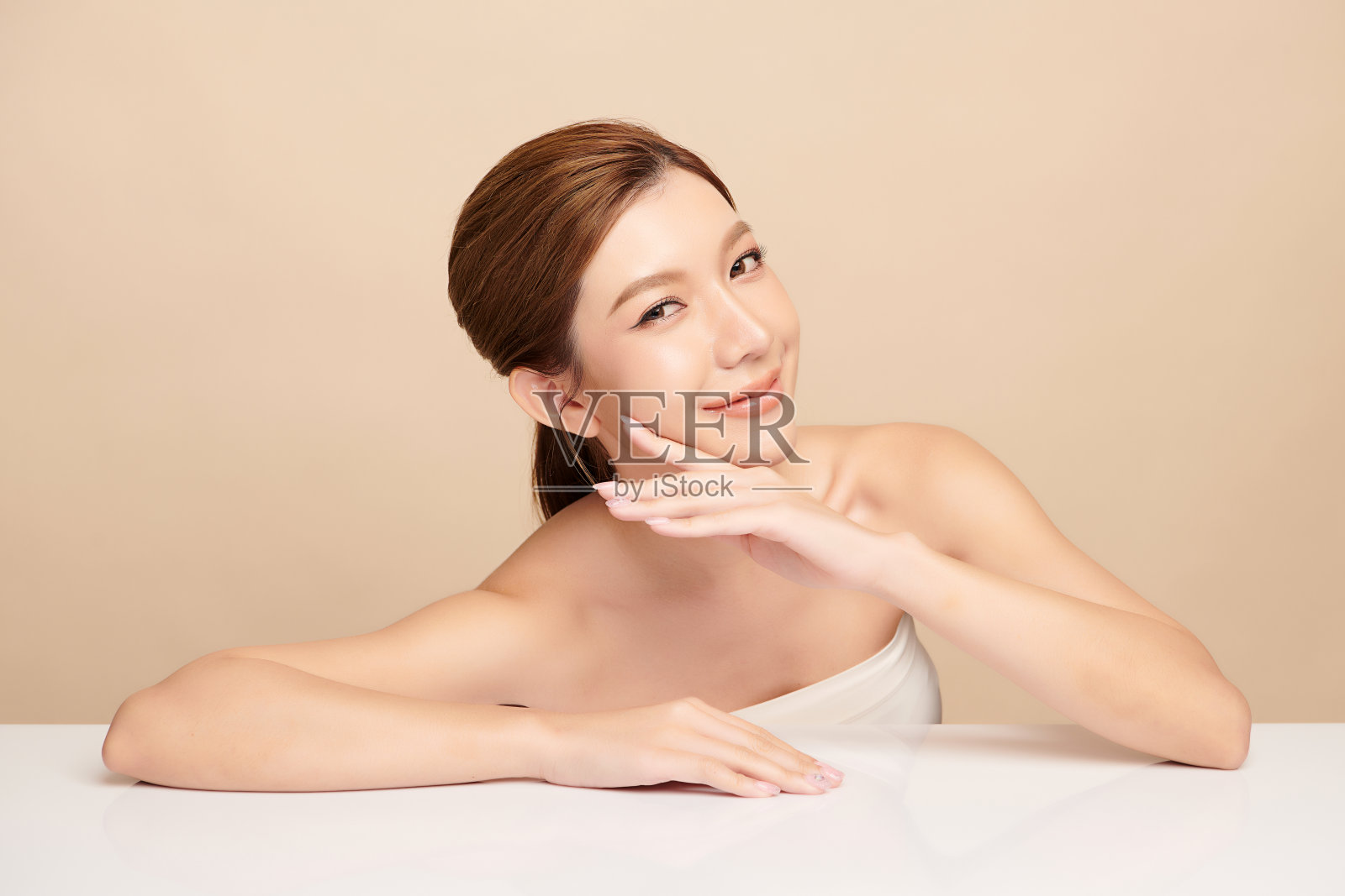 美丽的年轻亚洲女性干净新鲜的皮肤在米色背景，面部护理，面部护理，美容，美容和水疗，亚洲女性肖像。照片摄影图片