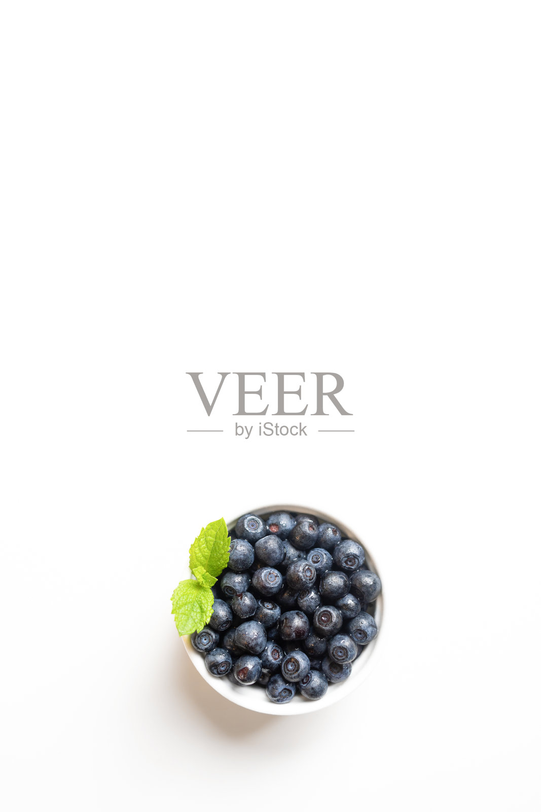 白色碗与森林蓝莓和薄荷叶在白色。副本的空间。前视图。垂直拍摄。照片摄影图片