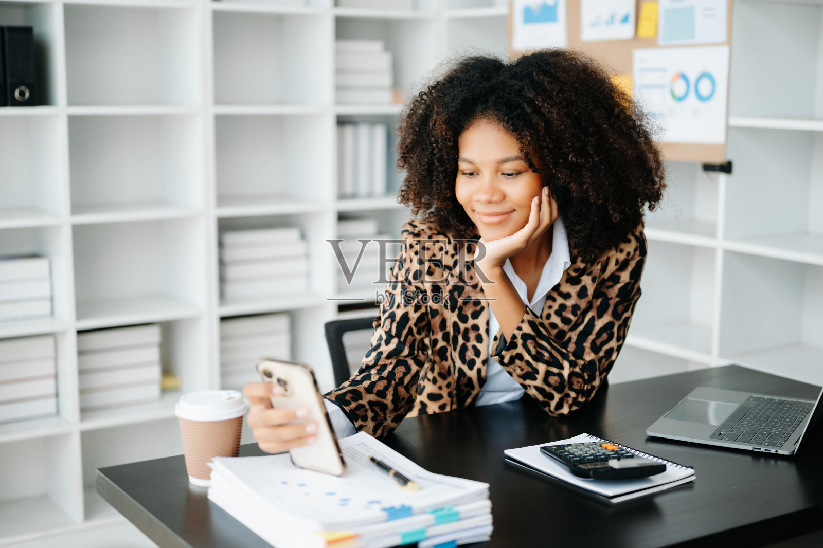 年轻的非洲妇女坐在黑色办公桌旁，用平板电脑和笔记本电脑打字照片摄影图片