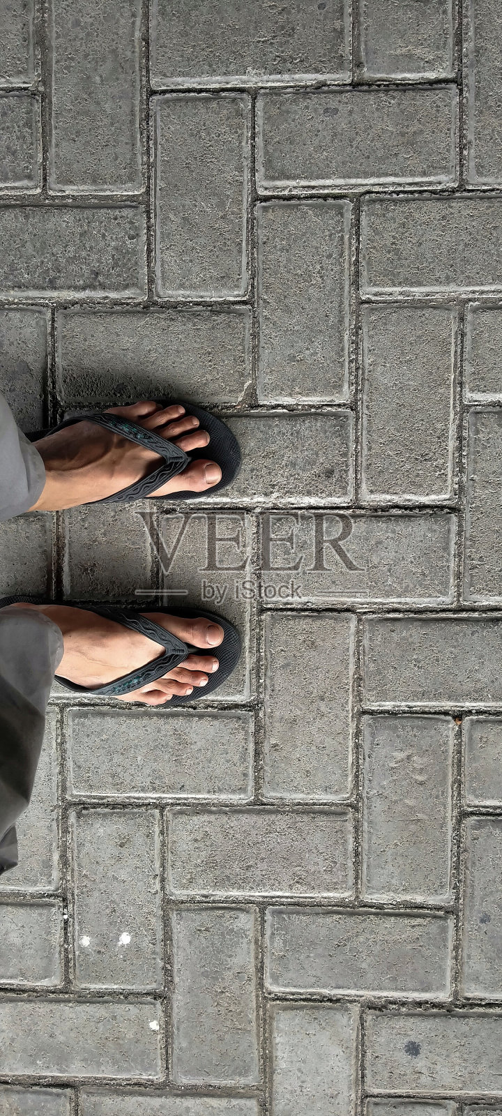 穿着黑色人字拖的脚踩在石板上照片摄影图片