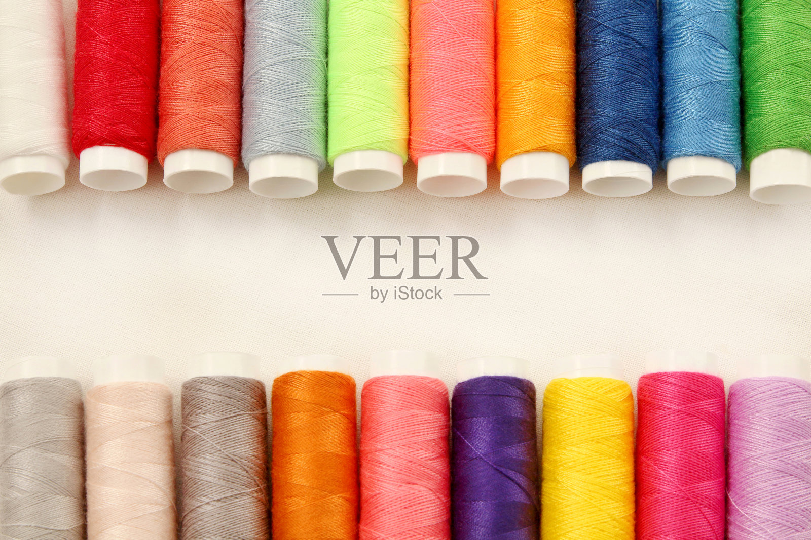 在白色棉织物上的多色缝纫线线轴，带有设计艺术作品的复制空间。照片摄影图片