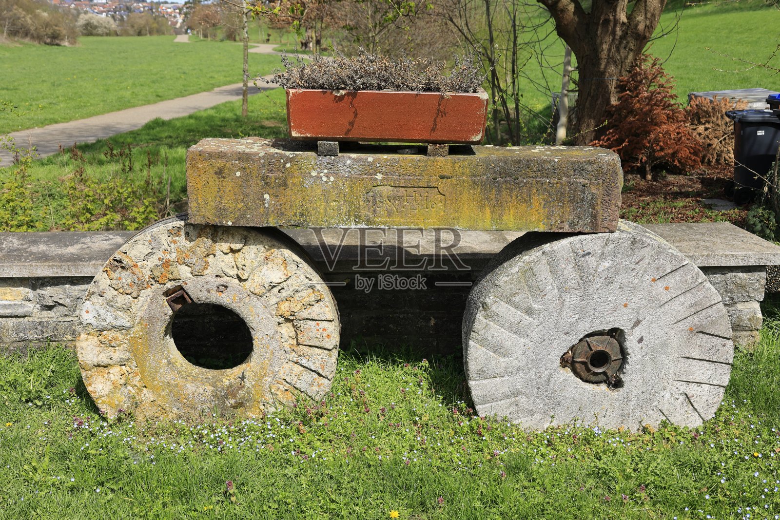 花盆立在两个用石头做的旧轮子上照片摄影图片