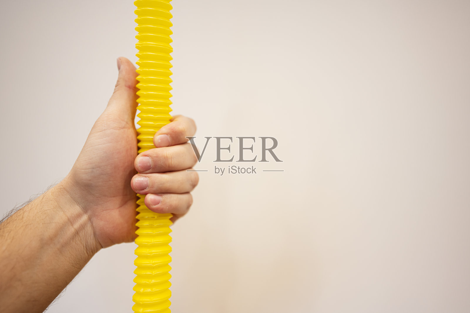 男性手拿着黄色软管的特写，白色背景与复制空间照片摄影图片