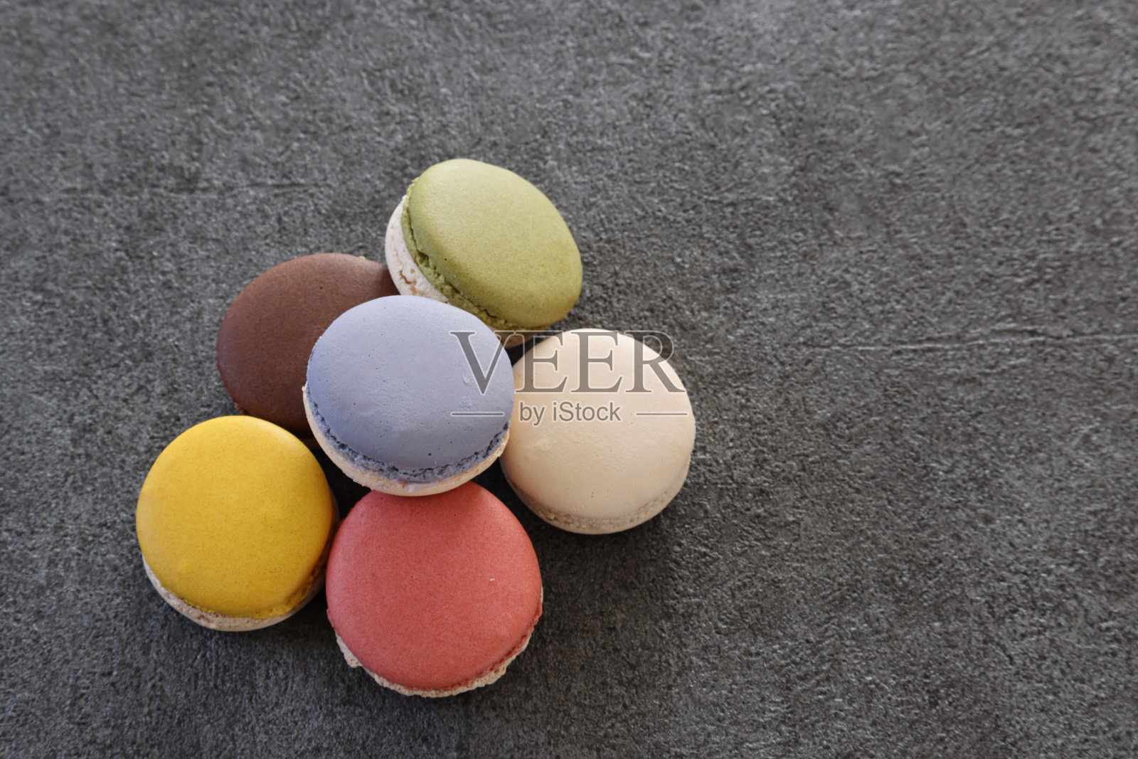 各种颜色的马卡龙被隔离在灰色的背景上。照片摄影图片