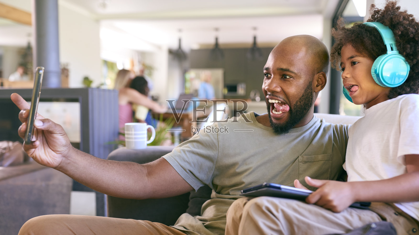 父子俩带着耳机在家里玩数码平板电脑，几代人都在后面照片摄影图片