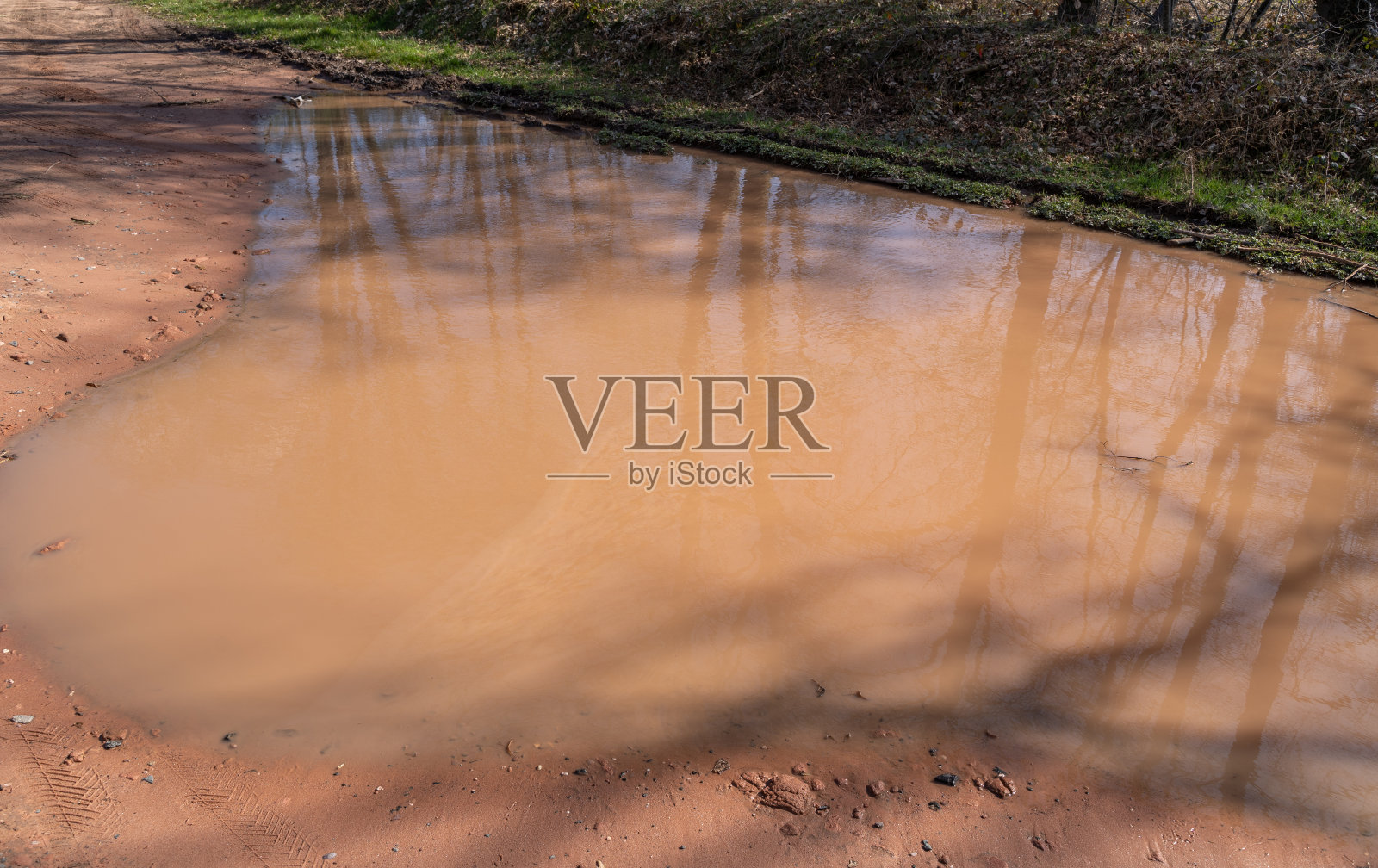 水坑与棕色雨水在沙质道路上的景观照片摄影图片