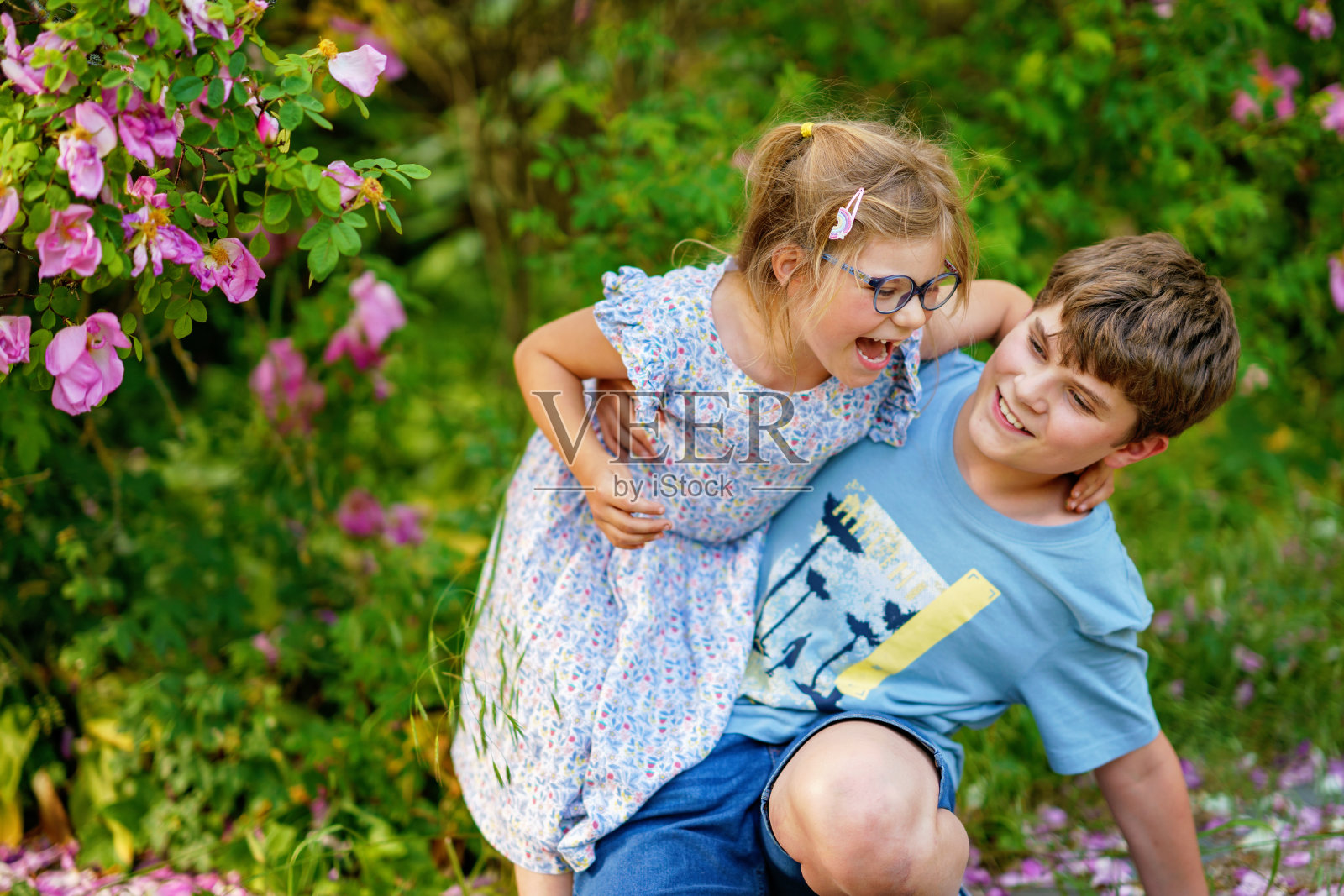 小学生男孩和小妹妹，学前班的女孩一起在公园里玩耍。两个快乐的孩子在阳光明媚的夏日里玩耍。相爱的兄弟姐妹。可爱的妹妹和弟弟。照片摄影图片