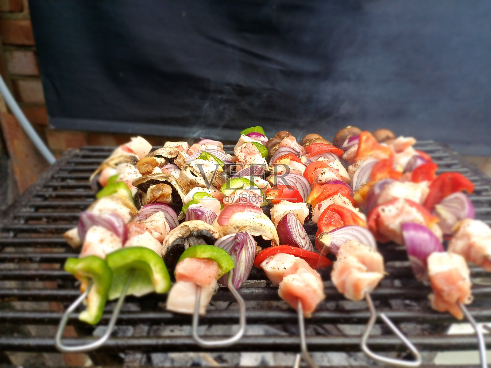 英国伦敦，炭火烧烤上的五花肉串，配上紫洋葱、红椒和青椒照片摄影图片