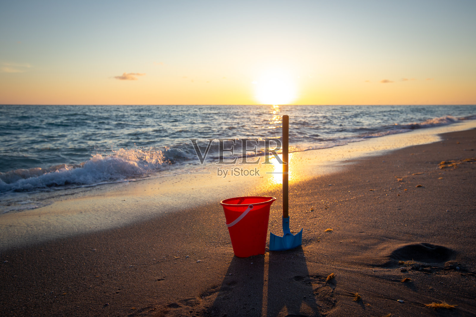 日落时分，水桶和铲子在沙滩上照片摄影图片