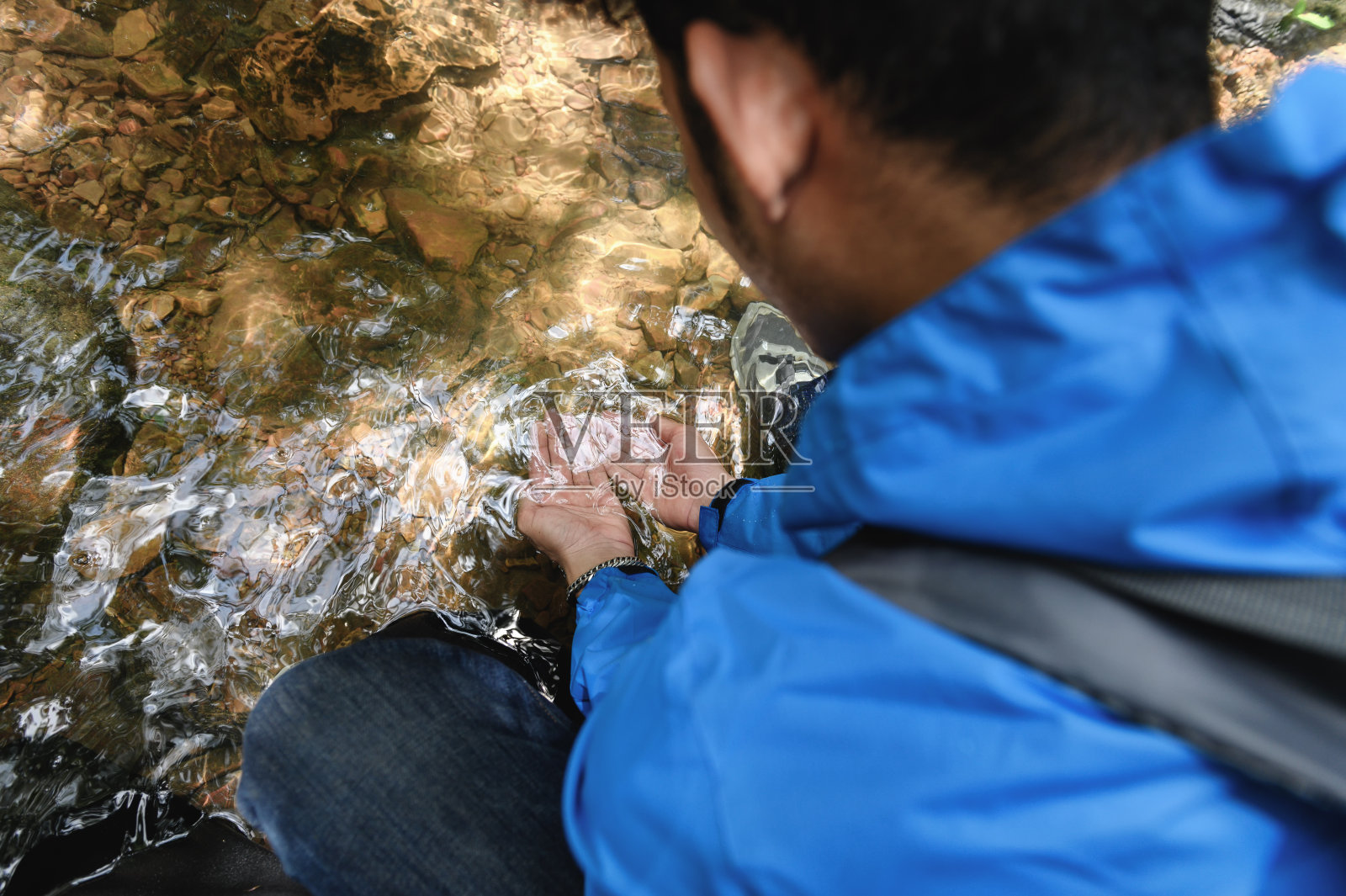 (特写)徒步者或旅行者从池塘里舀起一把纯净水，在山间溪水中洗脸时的手。长途旅行后使自己恢复精神。照片摄影图片