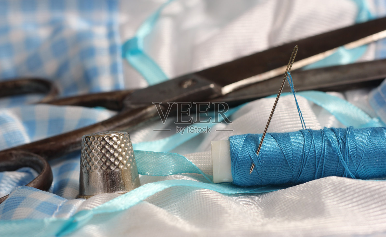 蓝线线轴，蓝白织物上的顶针和针照片摄影图片