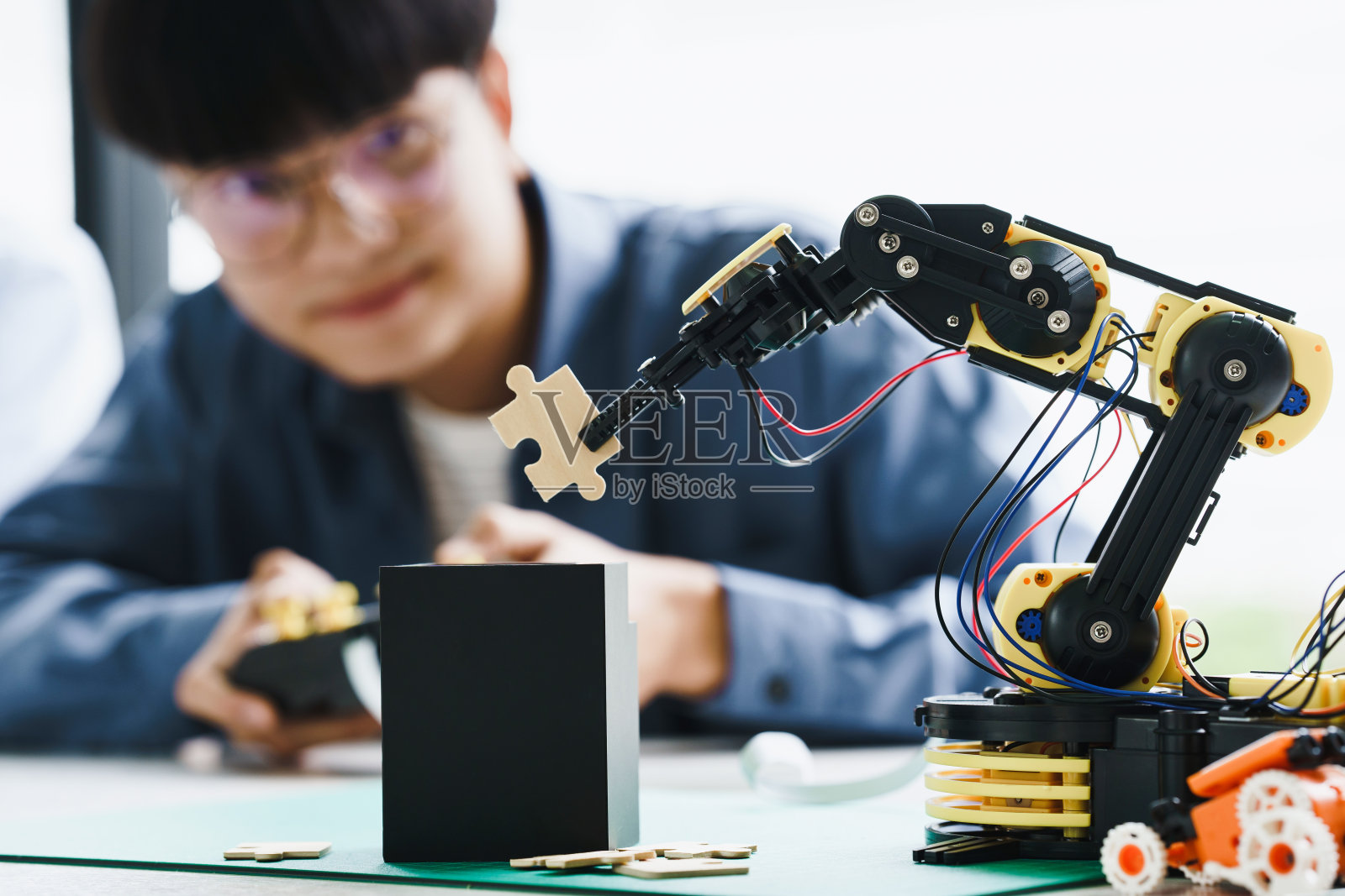 亚洲十几岁的学生在做或玩机器人手臂和机器人汽车的家庭作业项目，在家里组装电路和编码。机器人编程技术和STEM教育理念照片摄影图片