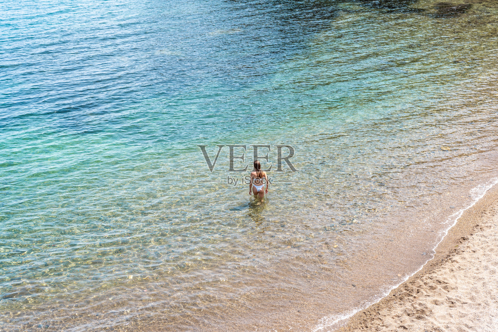 穿比基尼的女孩入海。照片摄影图片