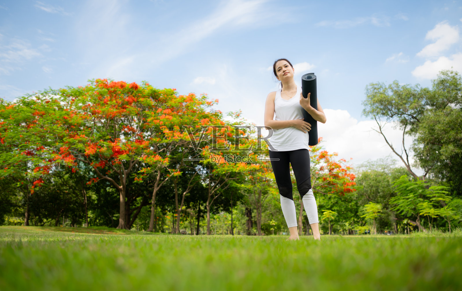 年轻女性在城市公园进行户外活动，瑜伽是她选择的活动。照片摄影图片