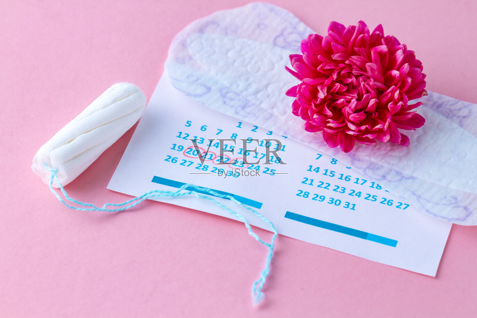 卫生棉条和月经护垫，女性日历和粉红色背景的鲜花。关键时期的卫生保健。月经周期规律照片摄影图片