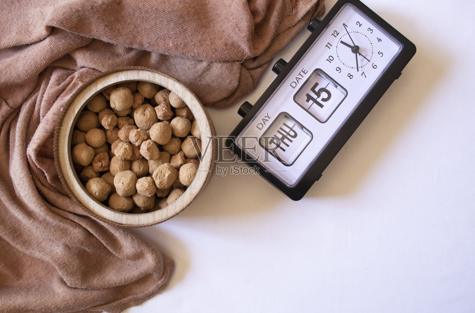 可食用的焦糖粘土石头在一个木制的圆形盘子旁边的手表在一个白色的背景平躺照片摄影图片