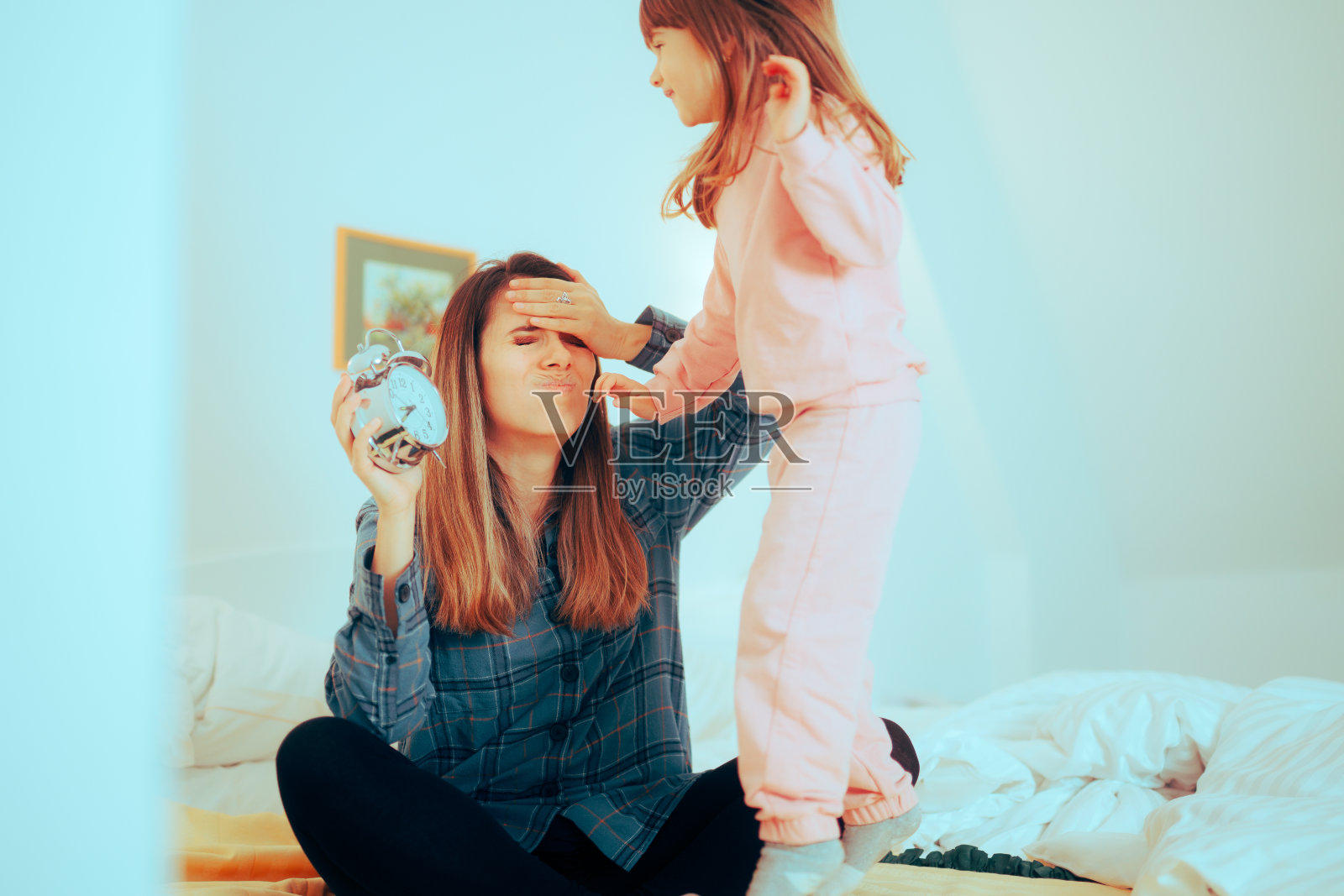 母亲告诉她过度活跃的女儿该睡觉了。照片摄影图片