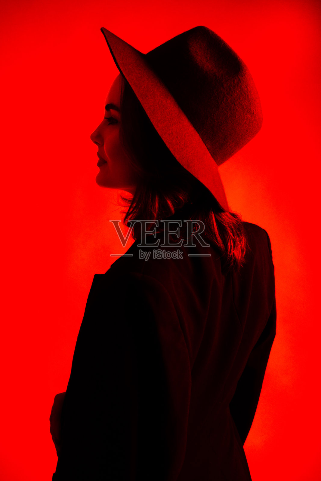 一个戴着帽子的女孩在红光下的剪影照片摄影图片