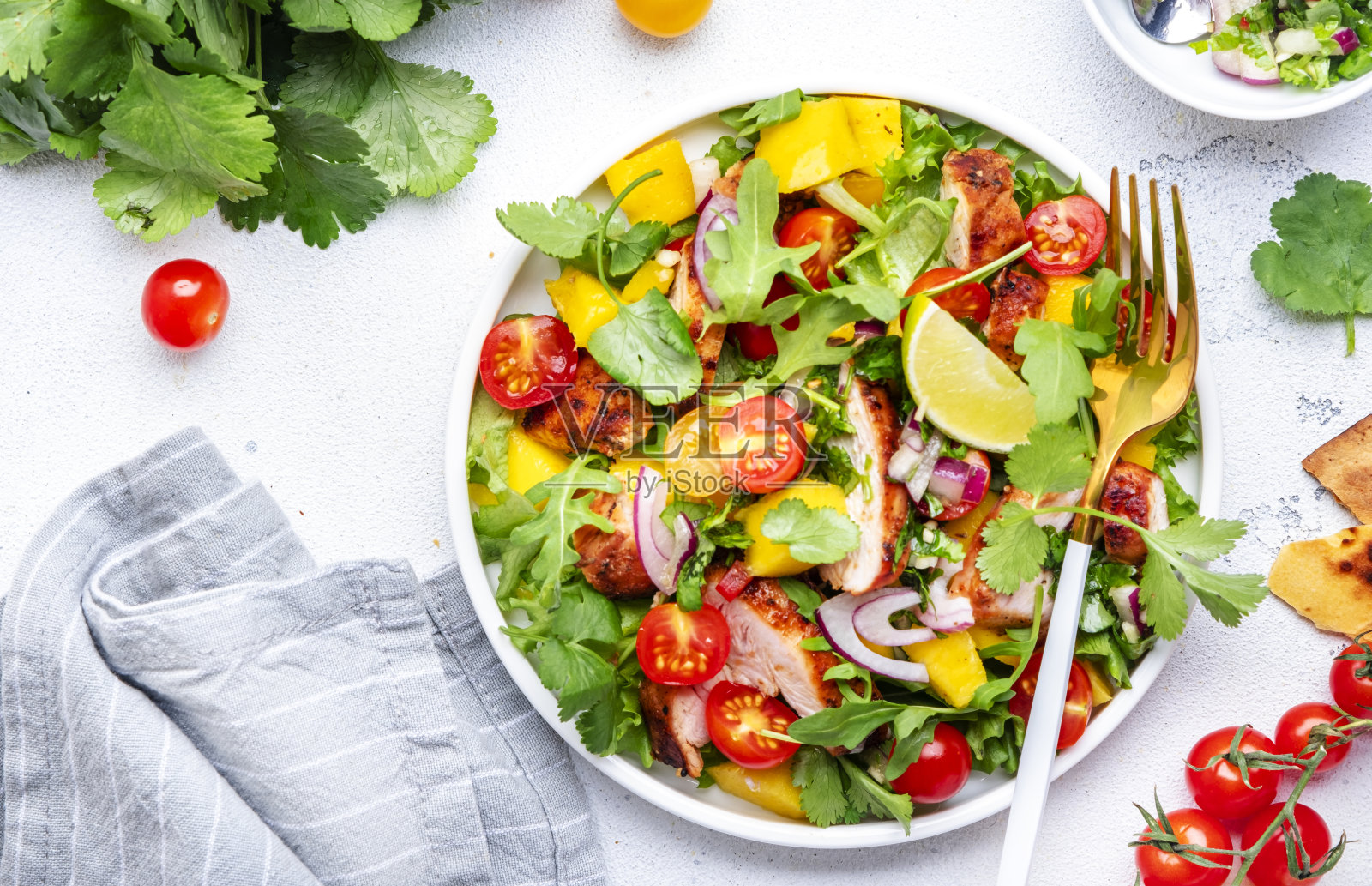 美味的沙拉，烤鸡和芒果沙拉，番茄，香菜，洋葱和生菜在墨西哥风格，白色厨房餐桌背景，俯视图照片摄影图片