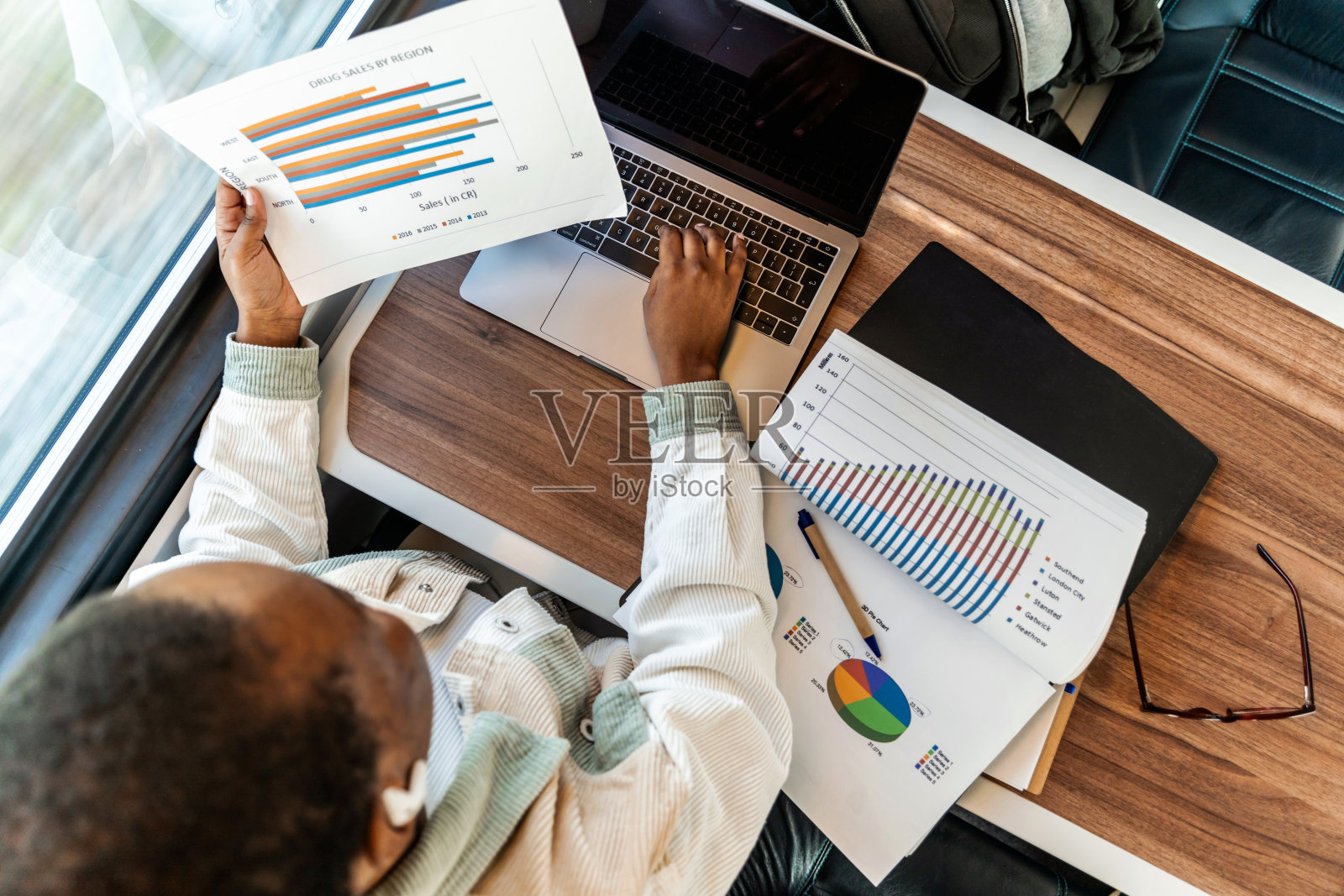 一位漂亮的年轻女子在乘火车去上班的路上，一边查看财务文件，一边用笔记本电脑工作。照片摄影图片