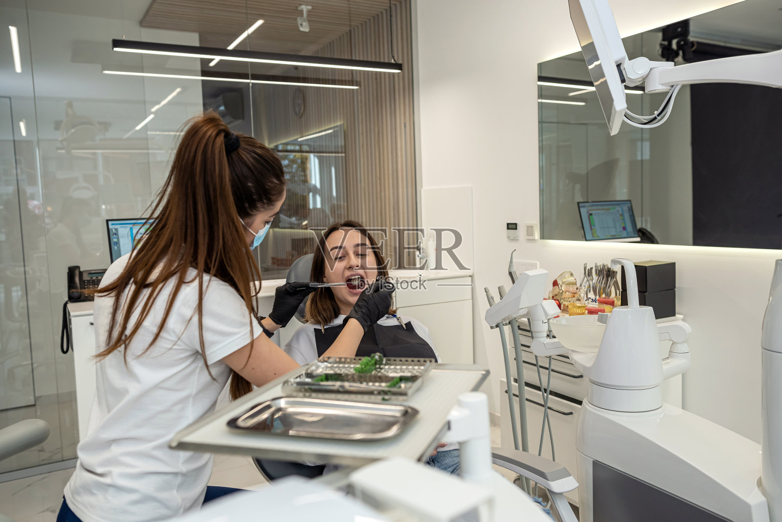 一名女牙医在她自己的牙科诊所为一名女病人工作。照片摄影图片