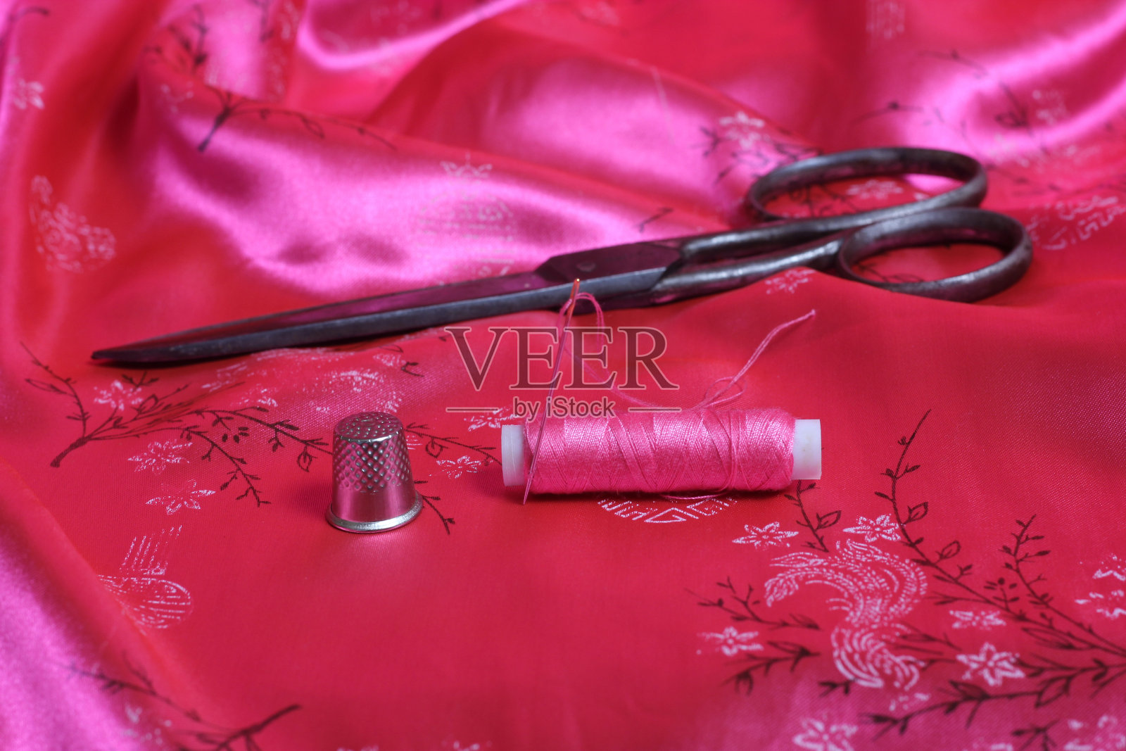 卷粉线和顶针上的复古粉红色缎面织物照片摄影图片