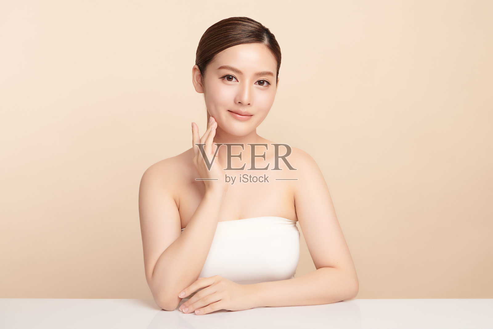 美丽的年轻亚洲女性干净新鲜的皮肤在米色背景，面部护理，面部护理，美容，美容和水疗，亚洲女性肖像。照片摄影图片