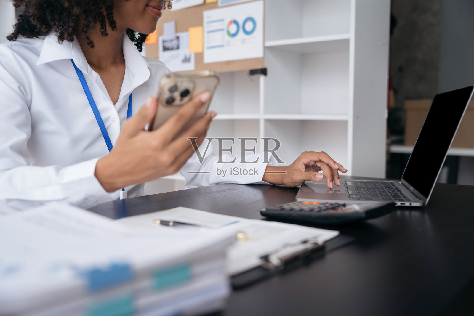 在现代办公室里，女商人用平板电脑和笔记本电脑处理办公桌上的文件。照片摄影图片