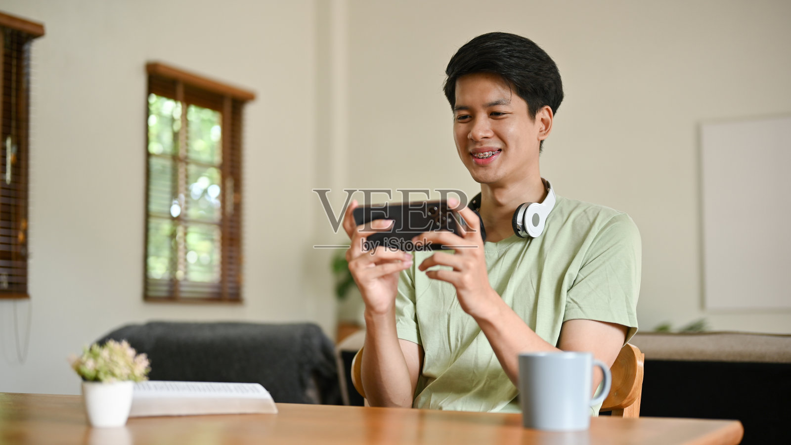 一个开朗的亚洲男人喜欢在家放松的同时玩手机游戏照片摄影图片