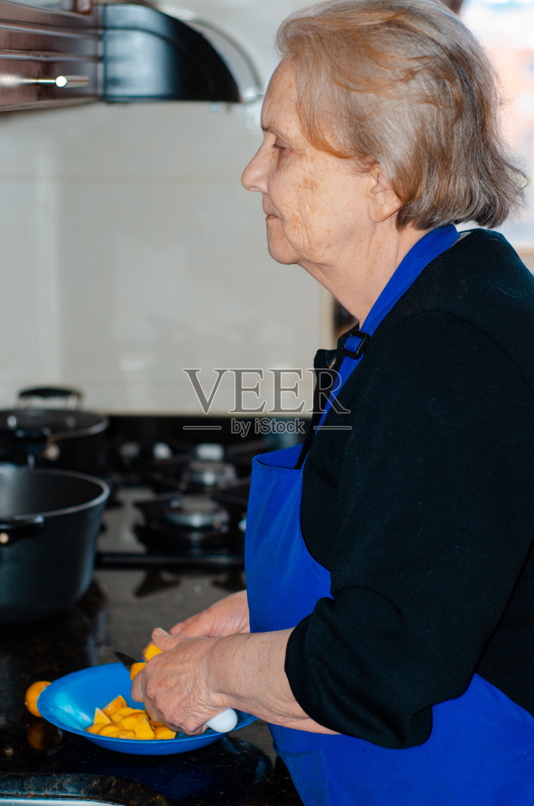 在厨房切土豆的成熟女人照片摄影图片