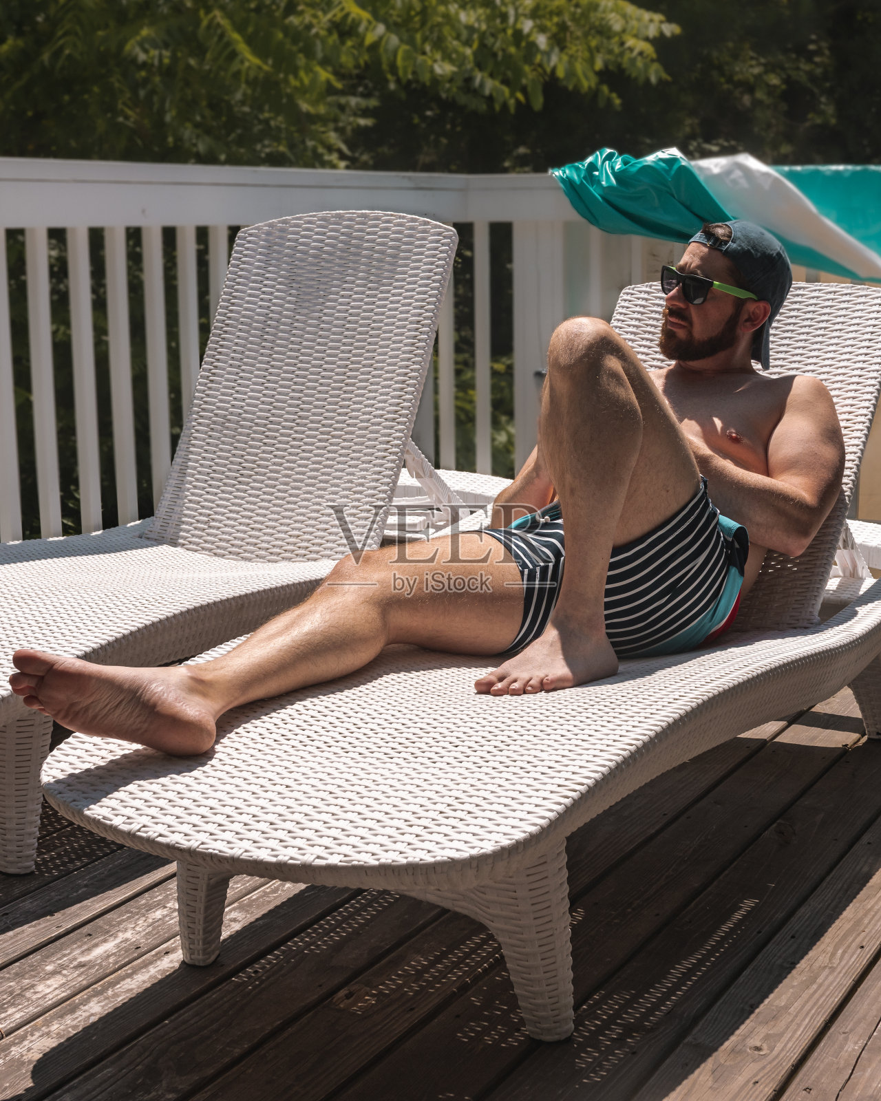 夏天，穿着泳装在日光浴躺椅上晒太阳的男子照片摄影图片