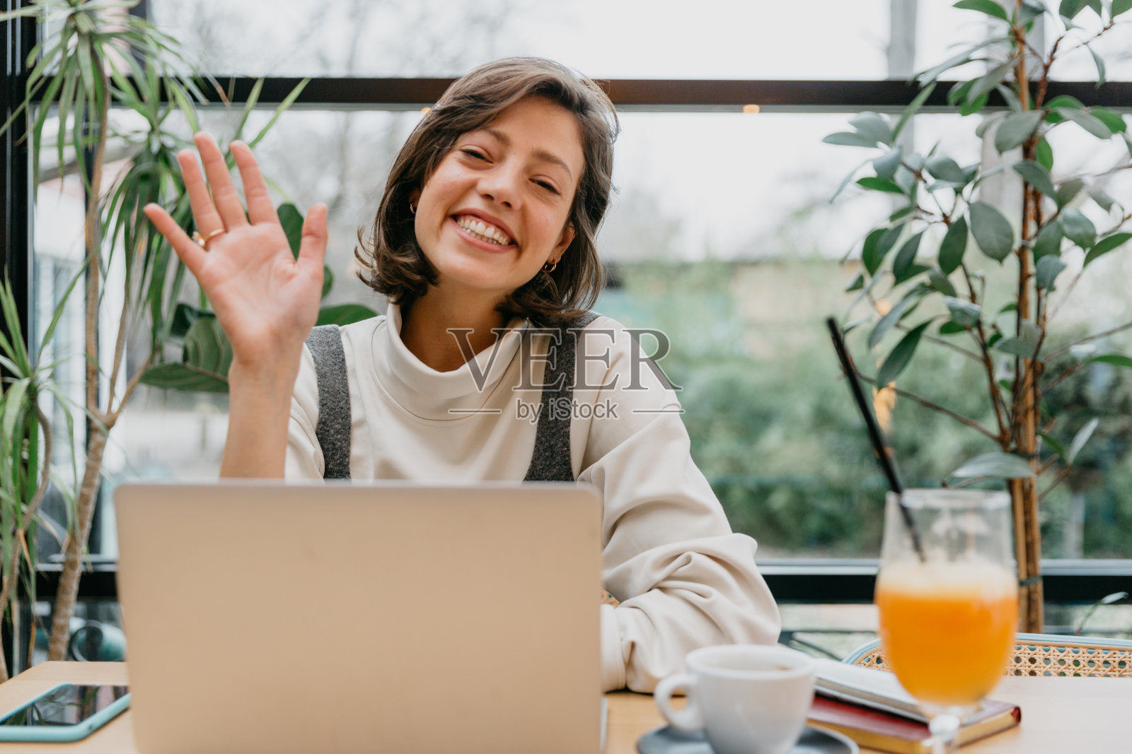 一个女人在餐厅里用笔记本电脑工作，象征着自由职业的自由和灵活性，人们可以选择自己的工作空间。照片摄影图片